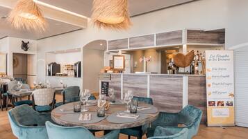 Un restaurant moderne avec des tables rondes, des chaises de couleur turquoise et un bar en bois.