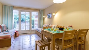 Un coin repas avec une table dressée pour deux personnes, un banc et un canapé agrémenté de coussins à rayures.