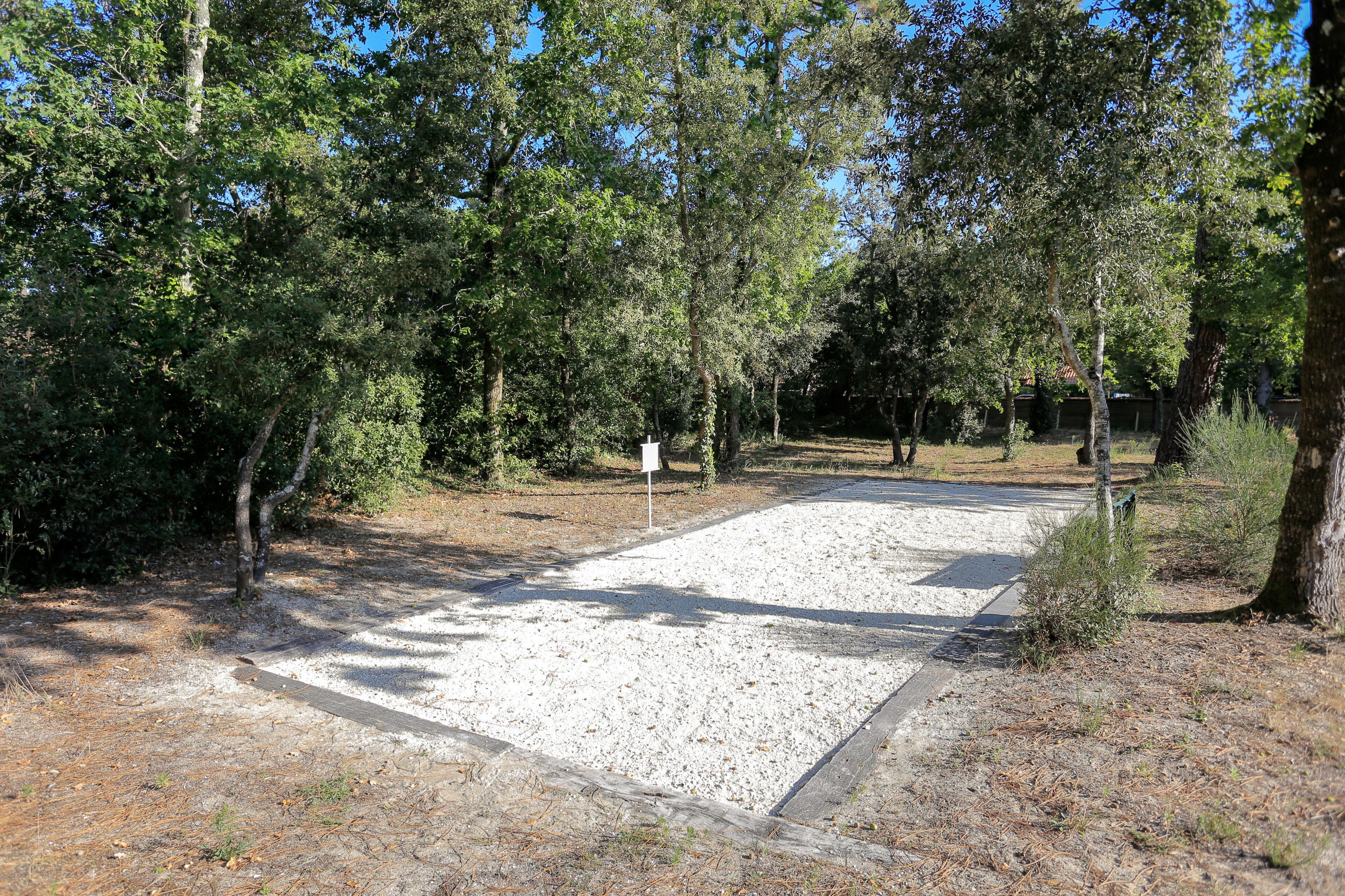 Un terrain de camping avec des chemins de gravier, des arbres et un panneau indicateur.