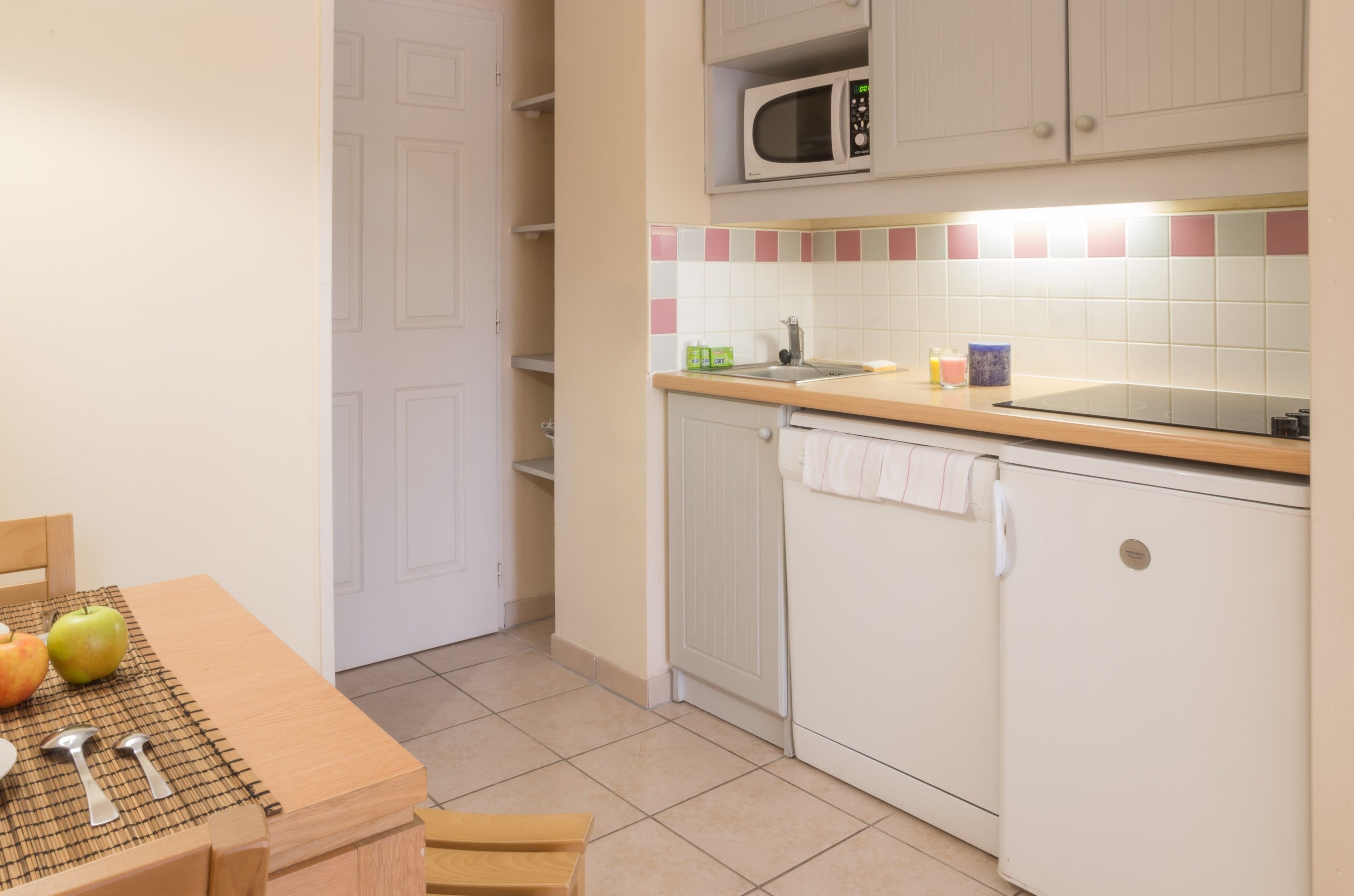 A kitchen with white cabinets, a microwave, a sink, and a tiled backsplash.