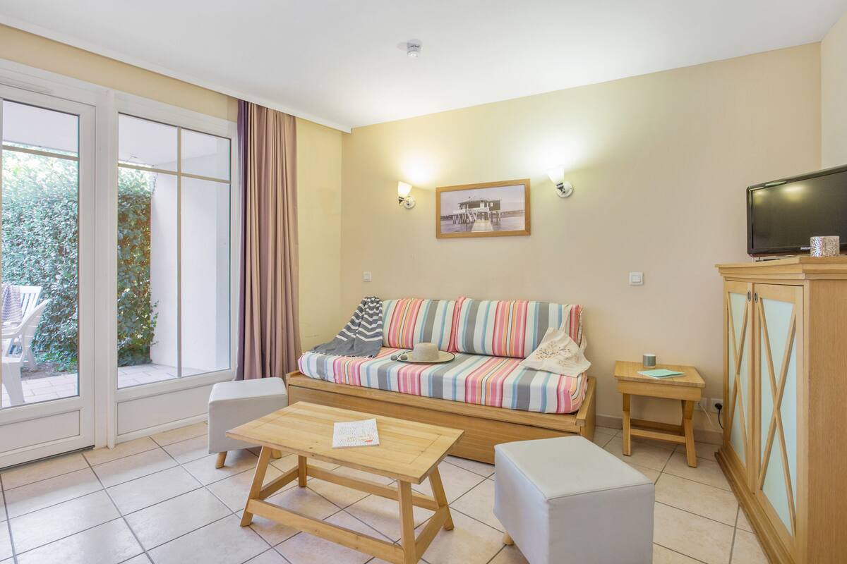 Ein gemütliches Wohnzimmer mit einem gestreiften Sofa, einem Holztisch, einem Fernseher und einem Schrank.