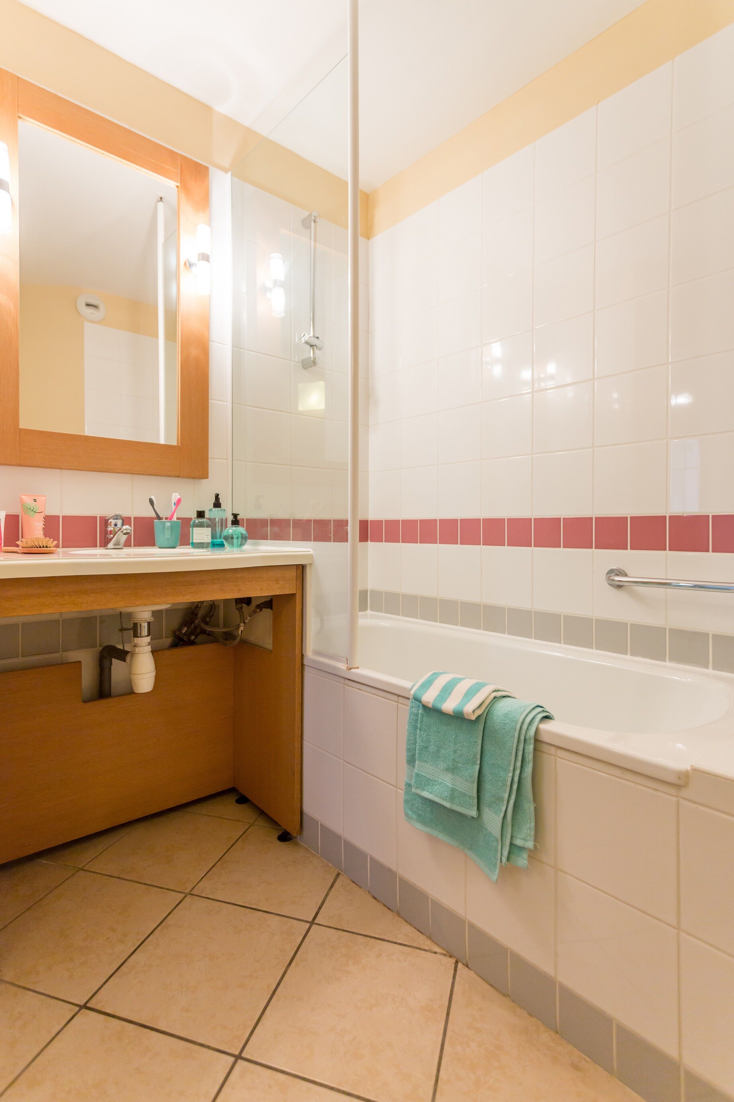 A bathroom with a sink, mirror, and bathtub.