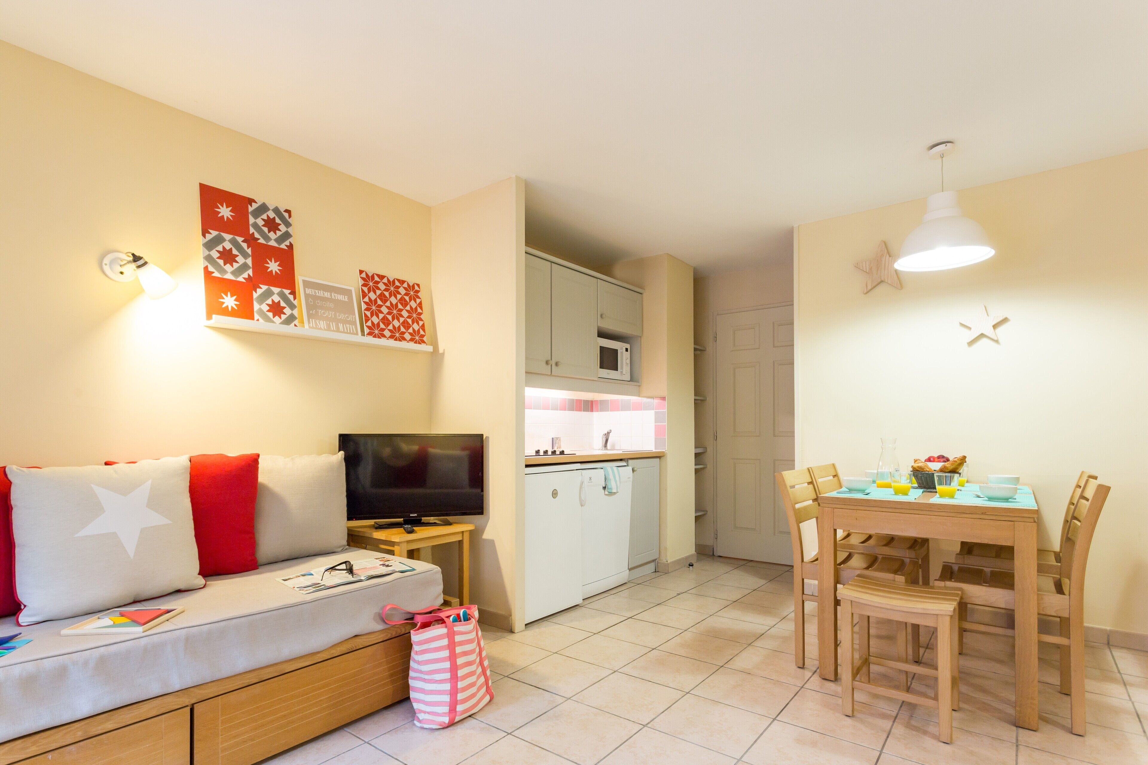 Ett kompakt bostadsutrymme med en soffa, TV, litet kök, matbord och stolar.