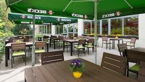 An outdoor seating area with green umbrellas, wooden tables, and chairs.