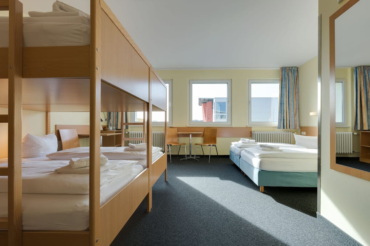 Een hotelkamer met stapelbedden, een bureau, een stoel en een raam.