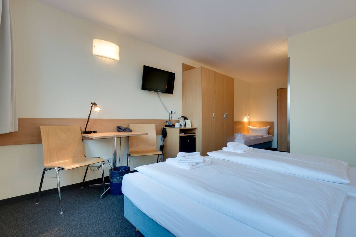Een hotelkamer met een bed, een bureau, een stoel, een televisie en een kledingkast.