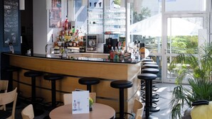 A bar area with stools, a counter with various bottles, and a chalkboard menu.