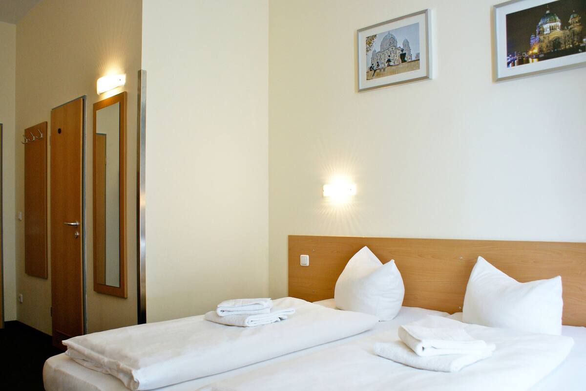 Een hotelkamer met een bed, twee nachtkastjes, een houten hoofdbord en twee wandlampen.