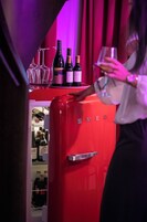 Uma geladeira vermelha com garrafas de vinho e copos em cima.