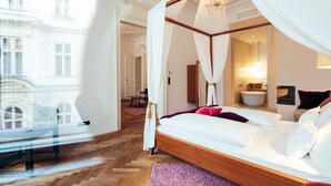 Una cama con dosel con sábanas blancas, un cabecero de madera y una alfombra morada.