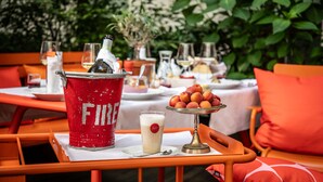Una mesa de comedor con un cubo rojo etiquetado 'FIRE', un vaso de leche y un plato de fruta.