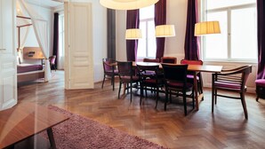 Un comedor con una mesa y sillas de madera, una lámpara colgante grande y vistas a una ventana con cortinas.