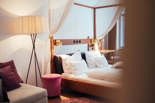 Una camera da letto moderna con testiera in legno, biancheria da letto bianca, un comodino e una lampada da terra.