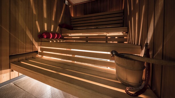 Una sauna con bancos de madera y un cubo de madera.