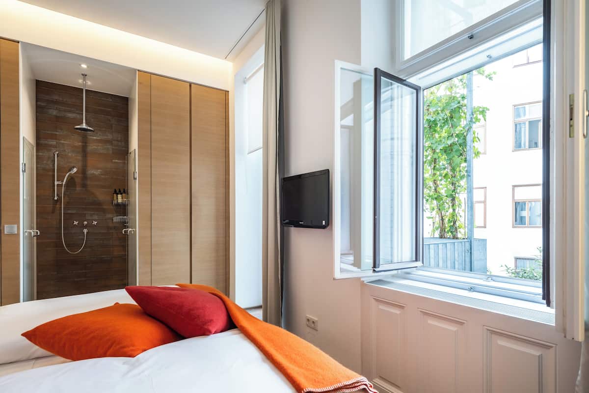 Un dormitorio moderno con cama, zona de ducha y ventana con vistas al exterior.