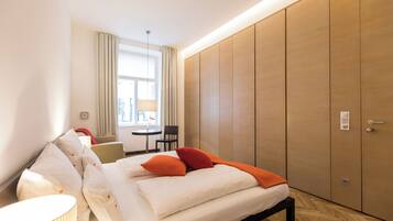 Habitación de hotel moderna con cama, mesita de noche, lámpara y vistas al exterior.