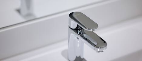 Un baño moderno con grifo de cromo y superficie reflectante.