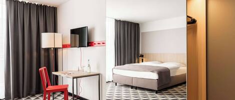 Une chambre d’hôtel comprenant un lit, un bureau, une chaise, une télévision et un miroir.