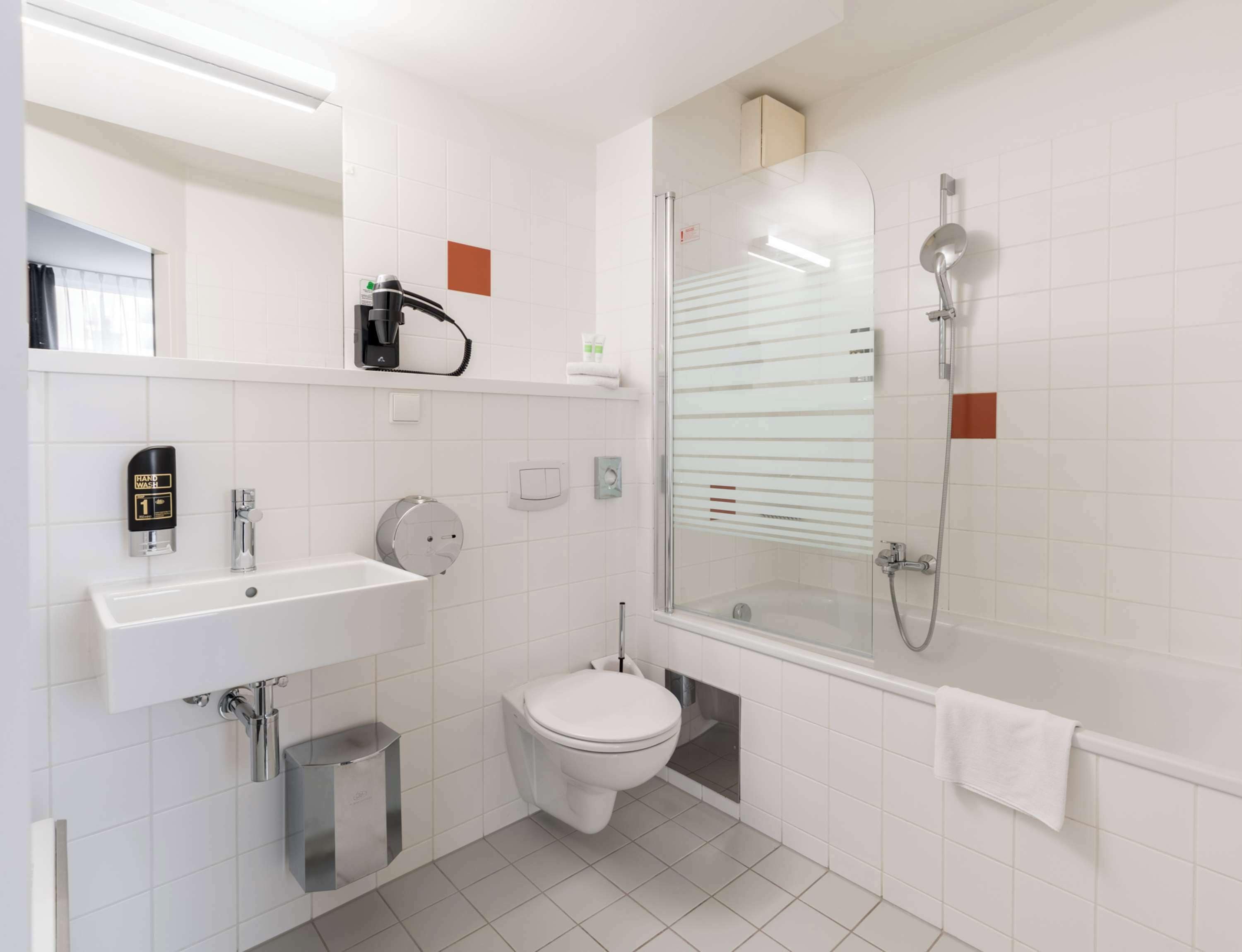 A modern bathroom with a toilet, sink, and shower.