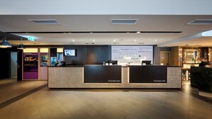 A hotel reception desk with a digital screen displaying a message, a vending machine, and a bar area.