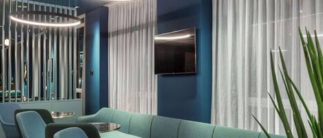 Un interior moderno con un sofá modular, mesas redondas y un televisor de pantalla plana montado en la pared.