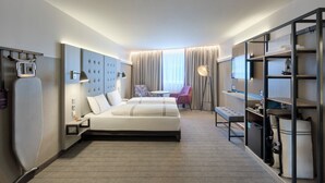 A hotel room with a bed, a desk, a chair, a wardrobe, and a window with curtains.