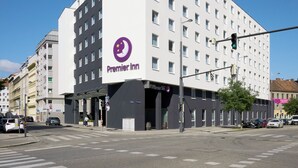 A modern hotel with a prominent Premier Inn logo, a flat facade, and a pedestrian crossing.