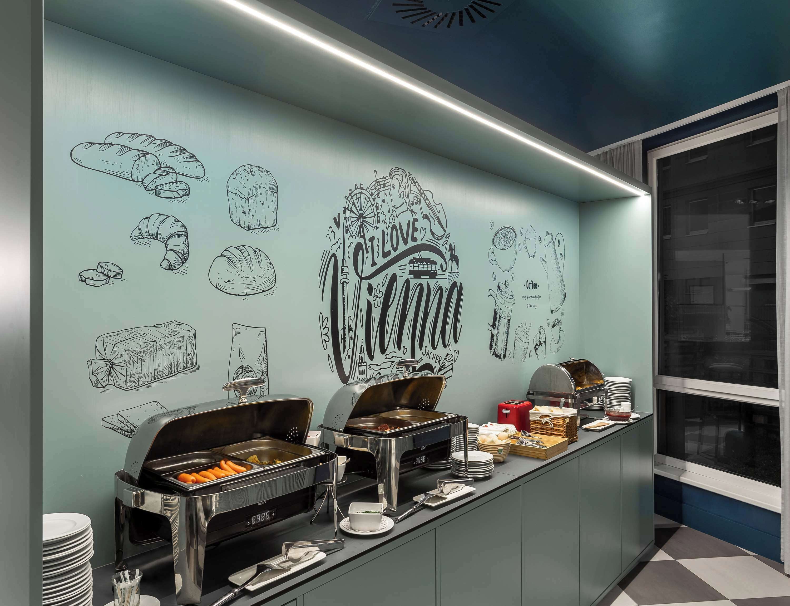 A buffet setup with various food items and a wall with food-related illustrations.