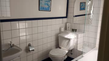 A bathroom with a white sink, toilet, and bathtub. There are two framed pictures on the wall, and the floor has a black and white tile pattern.
