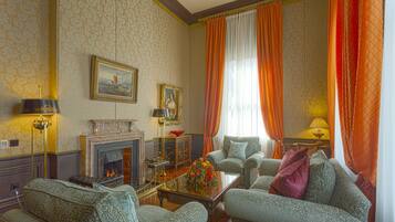 A traditional living room with patterned wallpaper, a fireplace, and classic furniture.