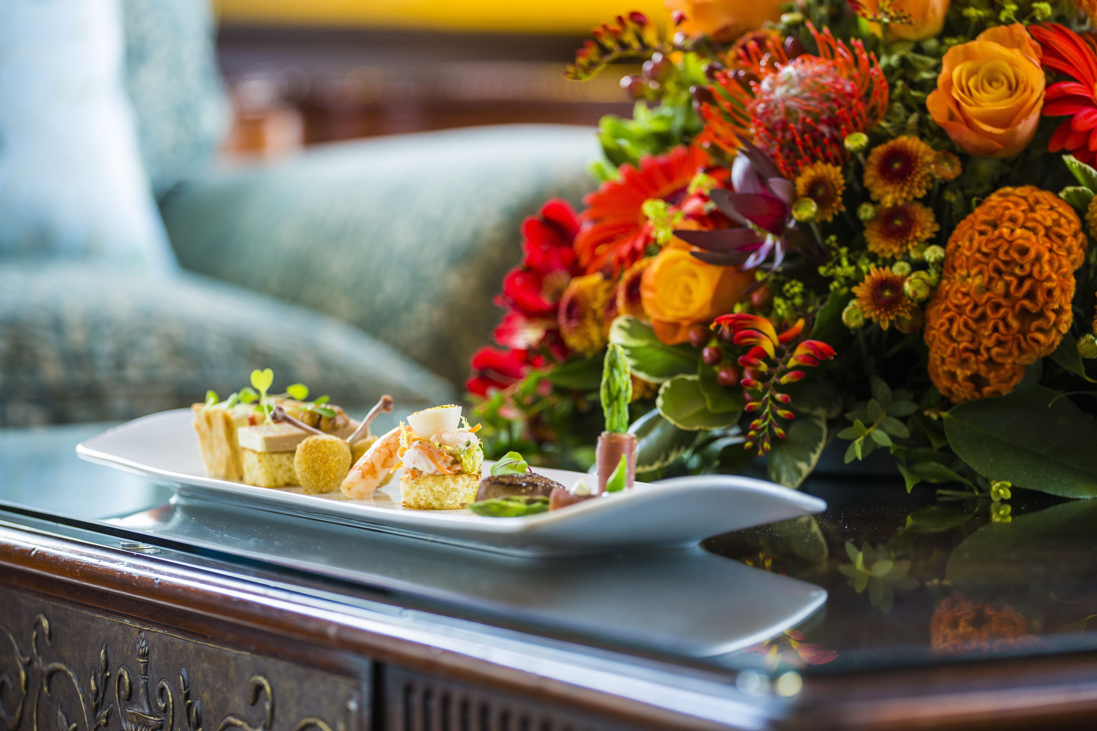 A table with a floral arrangement and a plate of appetizers.