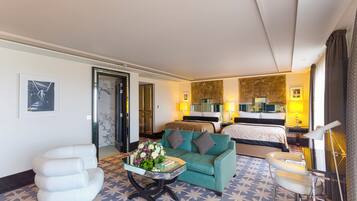 A hotel room with a bed, a sofa, a small table with flowers, and a chair.