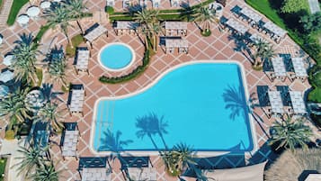 Una piscina al aire libre, sombrillas, sillones reclinables de piscina