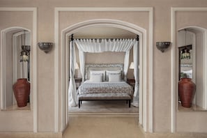 Un dormitorio con cama con dosel, un espejo grande y un florero en la mesita de noche.