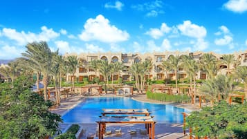 Un resort con piscina centrale, numerose camere e palme.