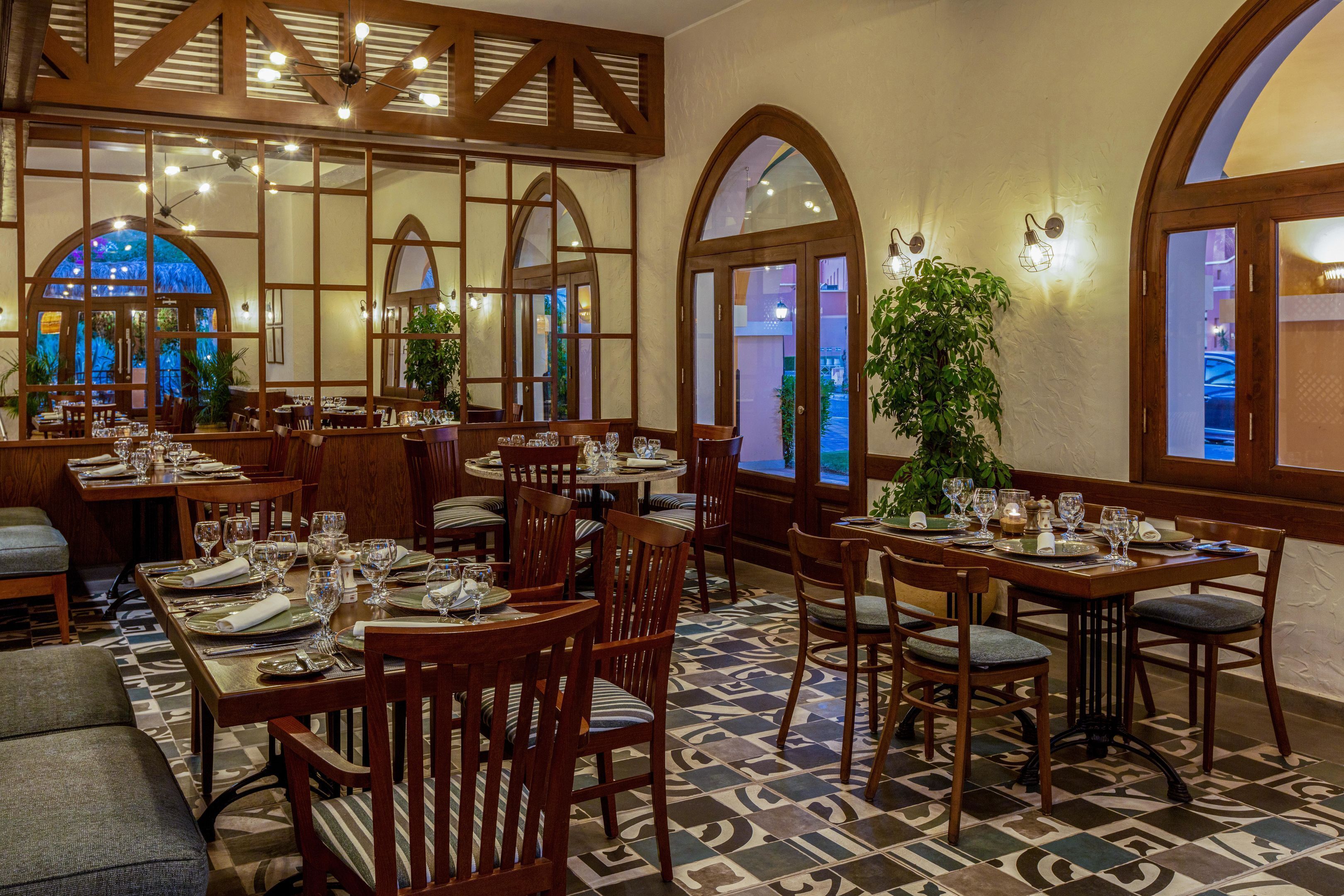 Un restaurant avec des meubles en bois, des fenêtres en arc de cercle et un sol à motifs.