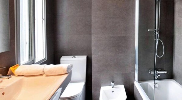 Un baño moderno con inodoro, lavamanos y ducha.