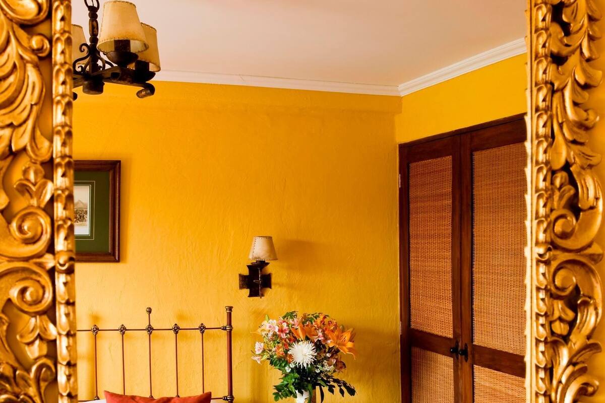 A room with a bed, a nightstand, a lamp, a mirror, and a door.