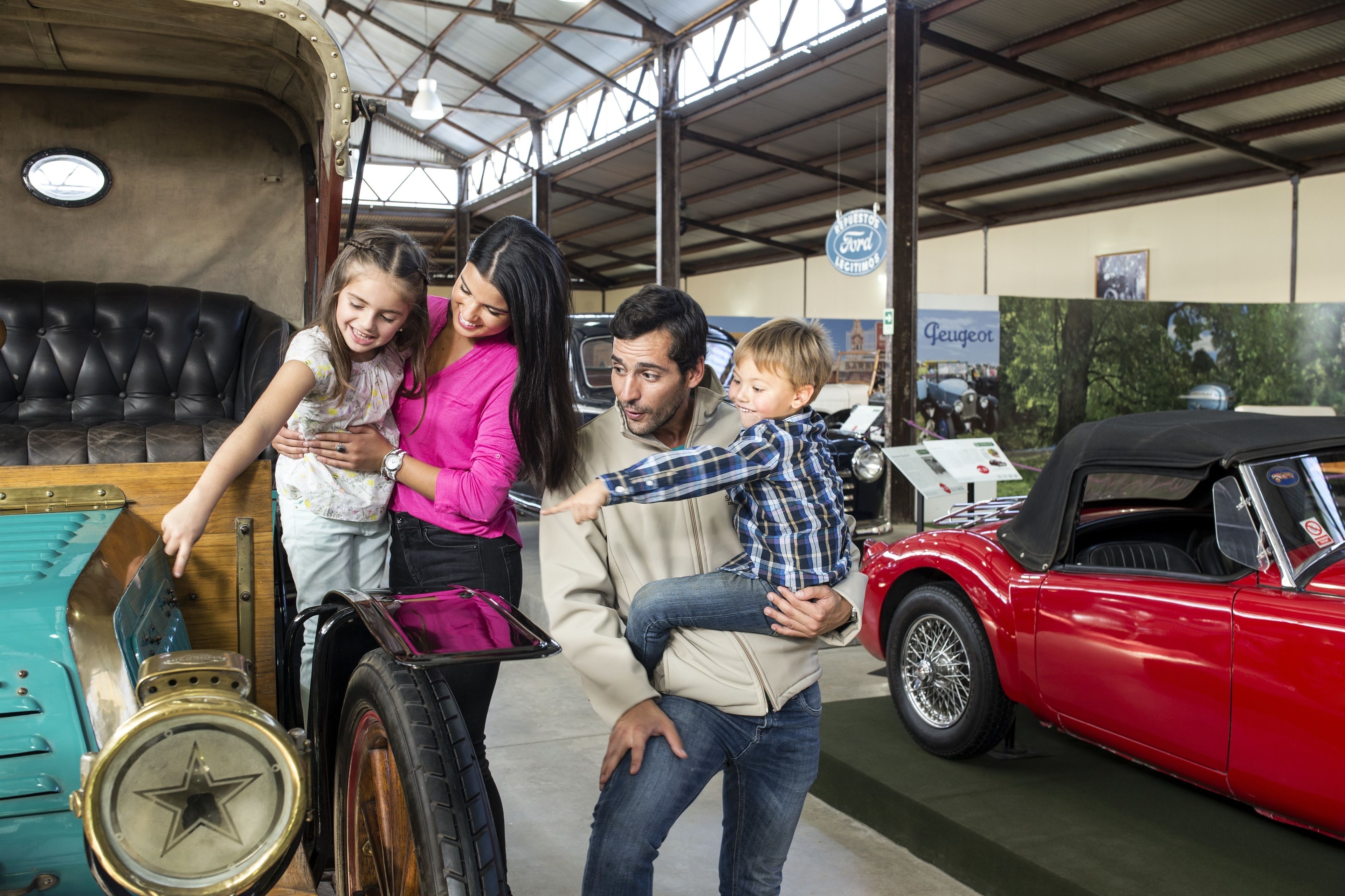 Una familia en un ambiente interior amplio, con un coche antiguo y un gran armario azul.