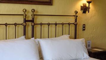 Una habitación de hotel con una cama, un cuadro en la pared, una mesita de noche y una lámpara.