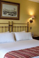 Una habitación de hotel con una cama, un cuadro en la pared, una mesita de noche y una lámpara.