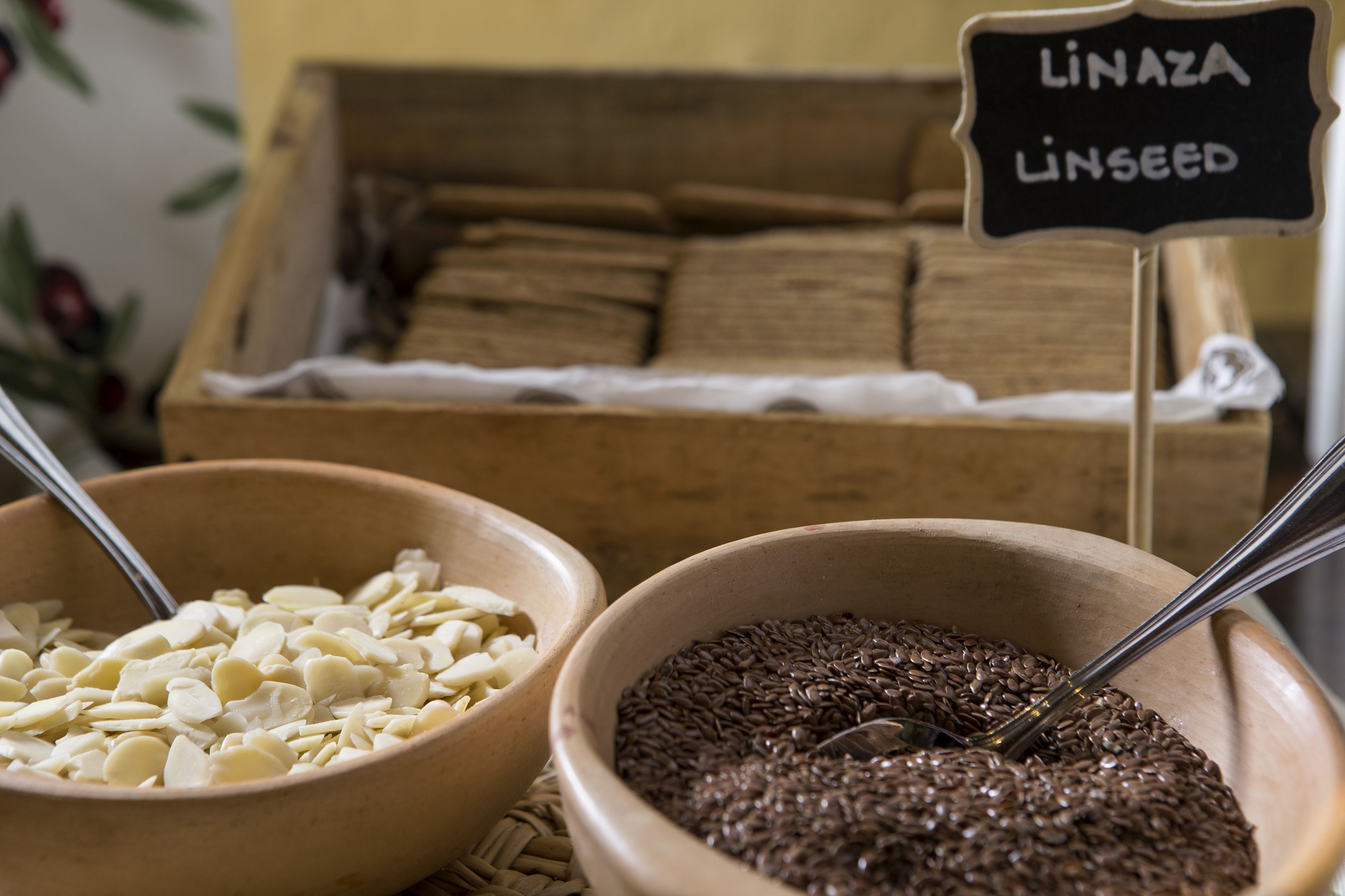 Zwei Schalen mit Nahrungsmitteln, eine mit Mandeln und die andere mit Leinsamen, mit einem Schild, auf dem 'LINAZA LINSEED' steht.
