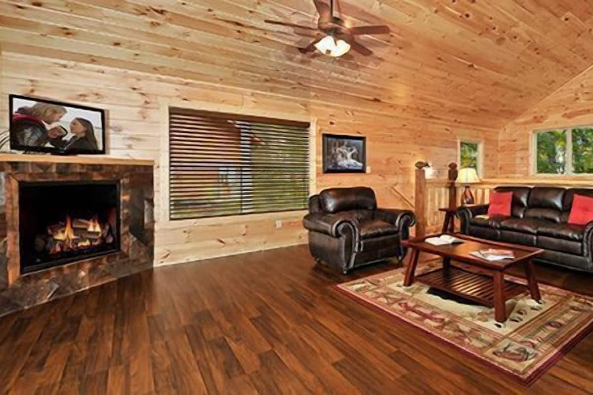 Acogedor interior de cabaña de madera con chimenea, muebles de cuero y paredes de madera.