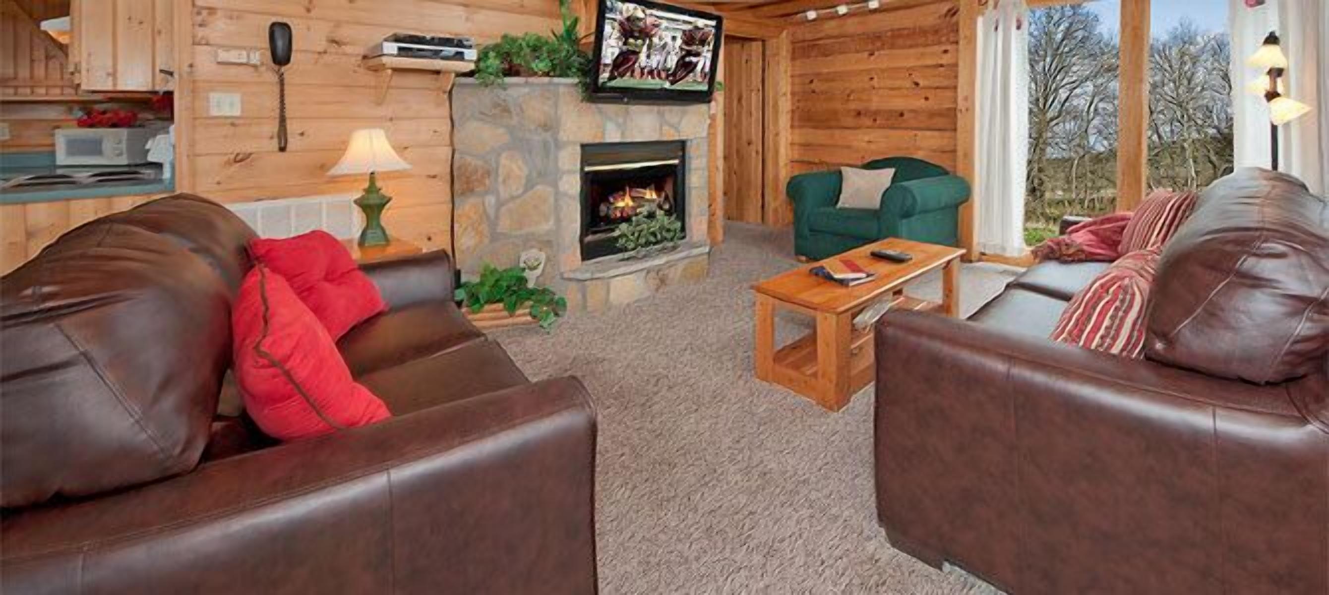 A cozy living room with leather sofas, a stone fireplace, and a television mounted on the wall.