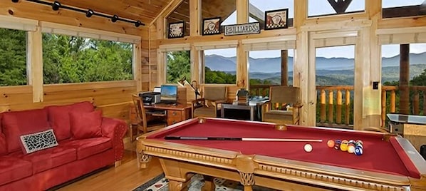 Ein Billardtisch in einem Holzraum mit einem roten Sofa und einem Schild mit der Aufschrift 'Billiards'.