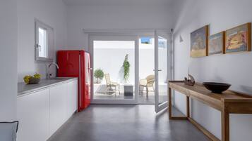 A modern kitchen with a red refrigerator, a wooden dining table, and a sliding glass door leading to a balcony with outdoor seating.