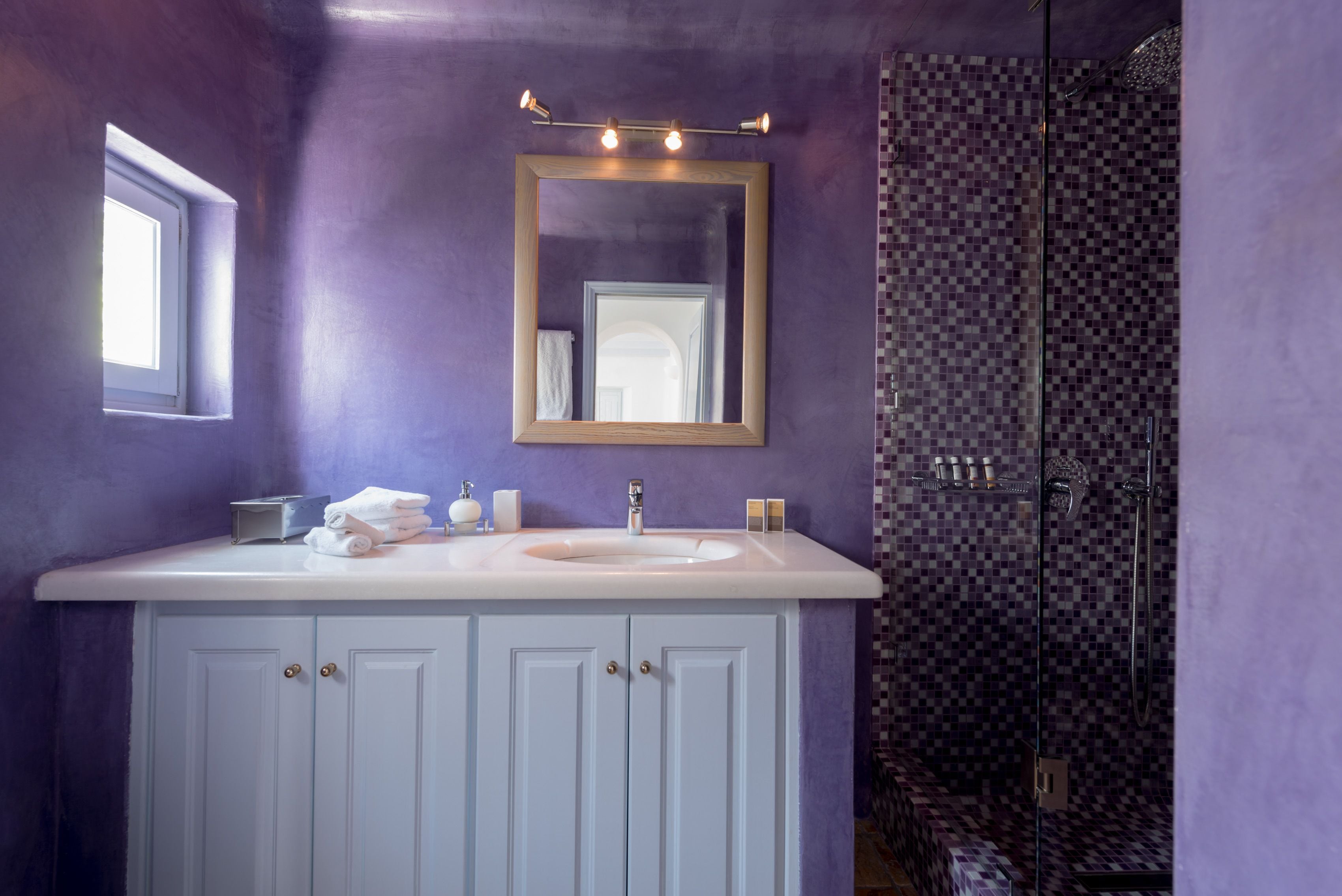 A bathroom with a white vanity, a mirror, and a shower with checkered tiles.