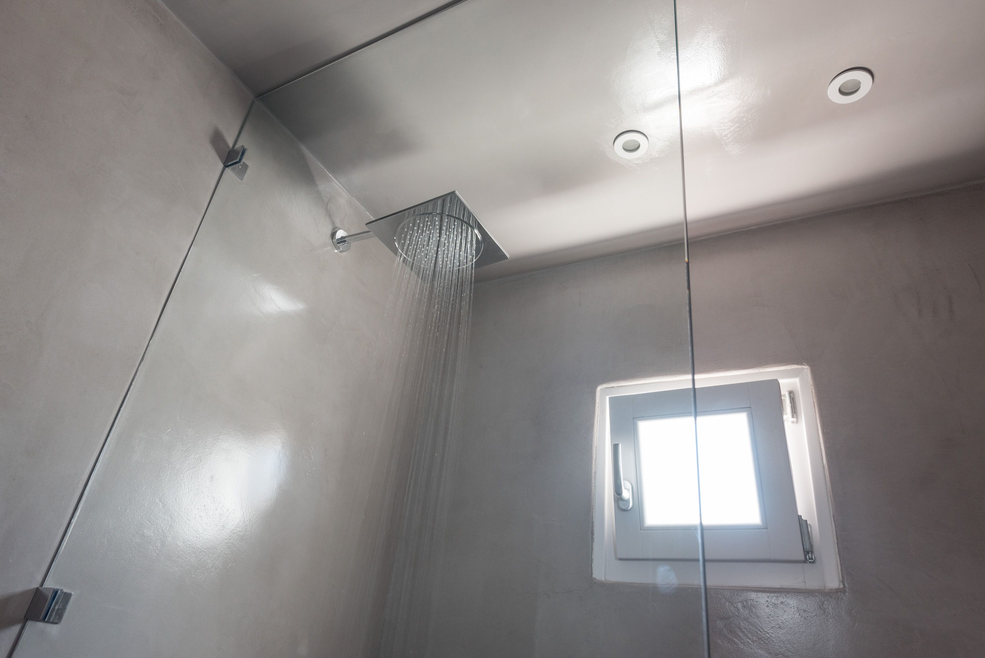 A shower with a square window, a visible showerhead, and a ceiling light fixture.