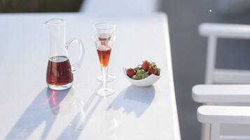 A table with a pitcher, two glasses, and a bowl of strawberries.