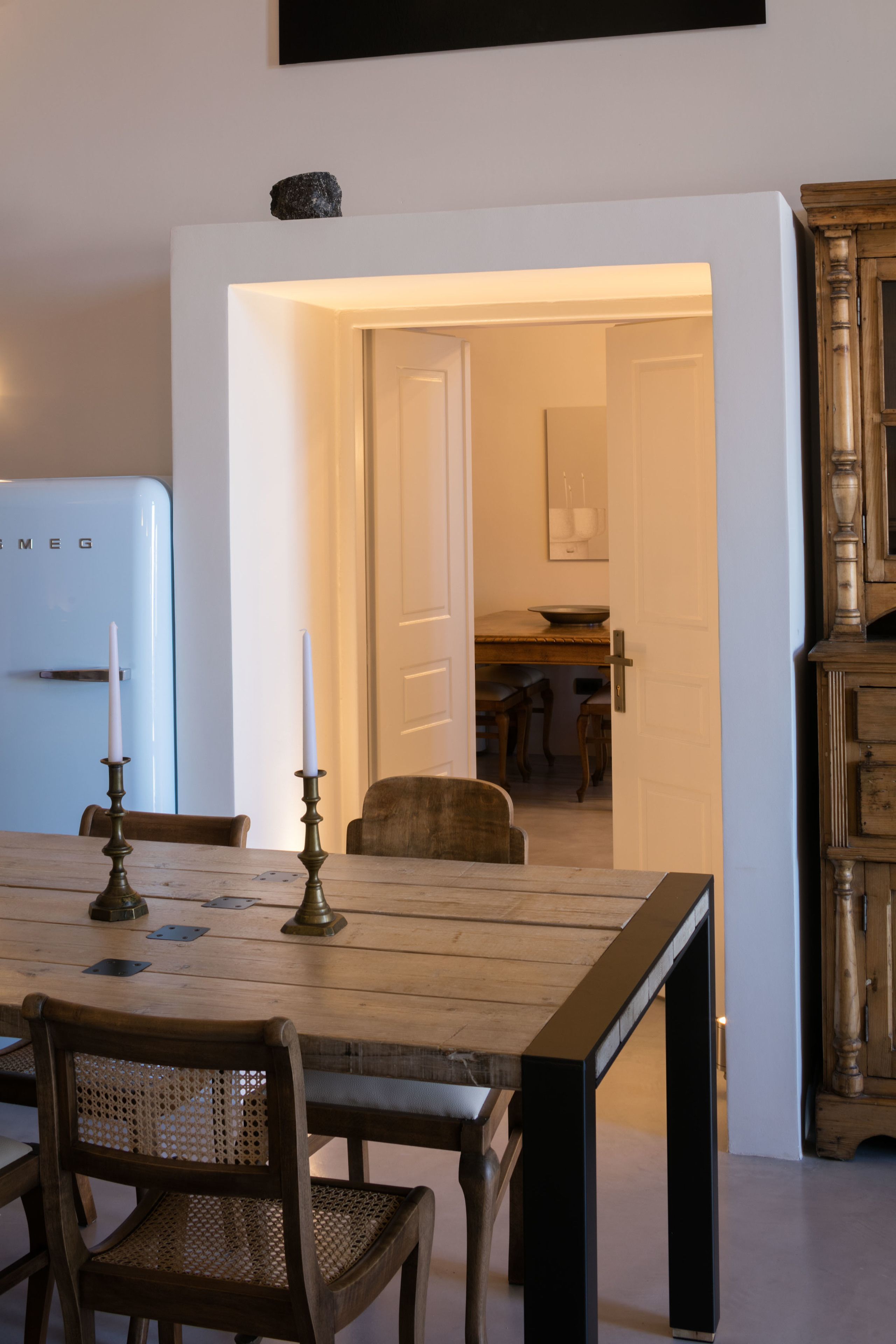 A dining area with a wooden table, chairs, and a vintage-style refrigerator.